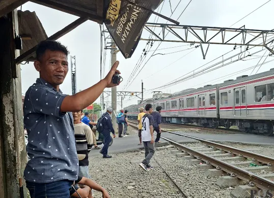 Khadafi saat menjaga perlintasan rel kereta liar di Perumahan Gaperi, Bojonggede, Sabtu sore, 26 Juli 2025. (Sumber: POSKOTA | Foto: Angga Pahlevi)