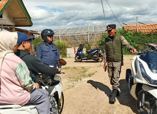 Petugas mengarahkan pengendara motor yang hendak melintas di kawasan tanah bergerak di Desa Cimanggu, Kecamatan Ngamprah, Bandung Barat pada Kamis, 31 Juli 2025. (Sumber: POSKOTA | Foto: Gatot Poedji Utomo)