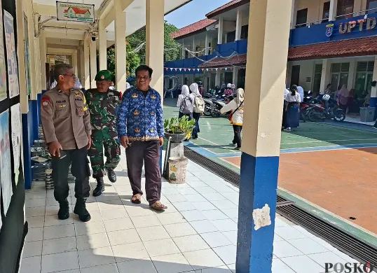 Anggota Bhabinkamtibmas Kelurahan Gandul, Kota Depok, bersama Babinsa melakukan pengamanan pendaftaran SPMB 2025. (Sumber: POSKOTA | Foto: Angga Pahlevi)