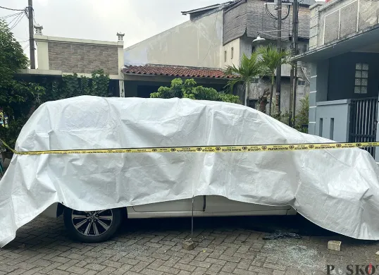 Kondisi mobil milik korban M yang tewas terbakar dipasang garis polisi di Perumahan Graha Pondok Kacang, Tangerang Selatan pada Selasa, 3 Juni 2025. (Sumber: POSKOTA | Foto: Primayanti)