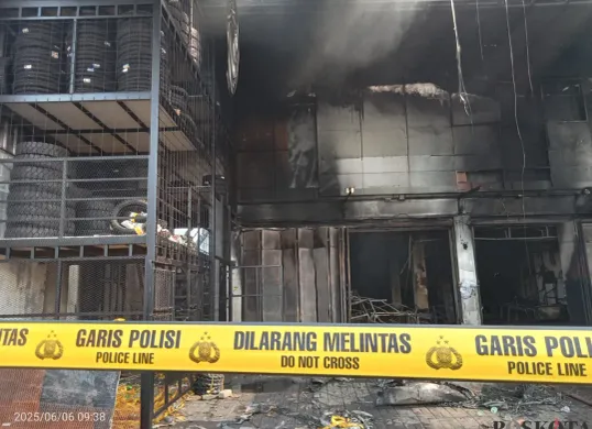 Garis polisi melintang di gudang ban Jalan Raya Jatimakmur, Pondok Gede, Kota Bekasi, yang ludes terbakar pada malam takbiran Idul Adha, Kamis 5 Juni 2025. (Sumber: Poskota/Nurpini Aulia Rapika)