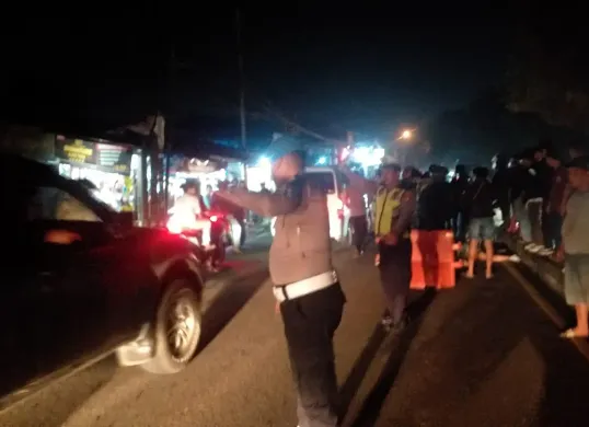 Petugas dari Polsek Cimanggis mengatur arus lalu lintas di lokasi kecelakaan yang menewaskan dua orang di Jalan Raya Bogor, Cimanggis, Depok pada Sabtu malam, 7 Juni 2025. (Sumber: Istimewa)
