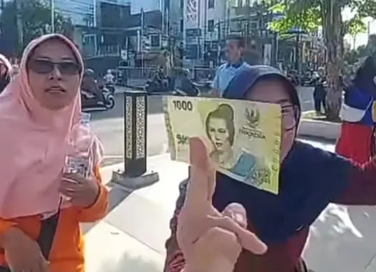 Seorang warga berhasil mendapatkan uang yang disebar dari atas langit Alun-Alun Jember. (Sumber: TikTok/@jawatimurpopuler)