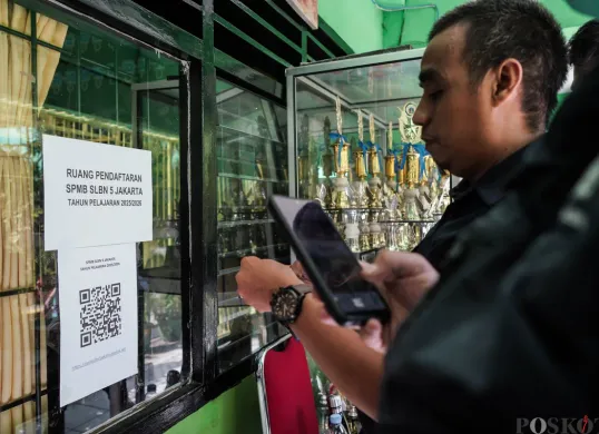 Orang tua siswa memindai kode pendaftran di Posko Sistem Penerimaan Murid Baru (SPMB) SLB Negeri 5 Jakarta, Senin, 16 Juni 2025. (Sumber: Poskota/Bilal Nugraha Ginanjar)