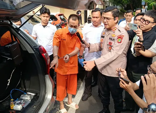 Tersangka kasus illegal access dengan modus SMS palsu menunjukkan alat yang digunakan untuk kejahatan phising di Mapolda Metro Jaya, Selasa, 24 Juni 2025. (Sumber: POSKOTA | Foto: Ali Mansur)