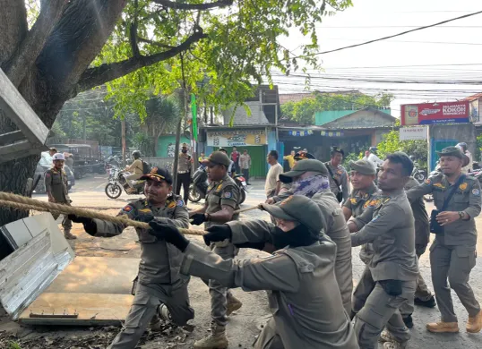 Satuan Polisi Pamong Praja (Satpol PP) Kota Depok menertibkan pedagang kaki lima liat mendiringan bangunan permanen atau tidak di sepanjang Jalan Pitara - Cipayung, Kota Depok. (Sumber: Poskota/Angga Pahlevi)