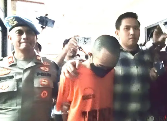 Mochamad Ichsan Ezra Candra, 23 tahun, pelaku penganiayaan ibu kandungnya sendiri di Bekasi Timur tertunduk saat digiring polisi. Ia diketahui kerap mengonsumsi obat berbahaya jenis eksimer. (Sumber: Poskota/Nurpini Aulia Rapika)