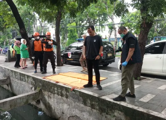 Anggota Polsek Koja dibantu petugas ambulans melakukan olah TKP pengangkatan jenasah dari saluran air ke kantung jenasah, Senin, 10 Maret 2025. (Sumber: Dok. Polsek Koja)