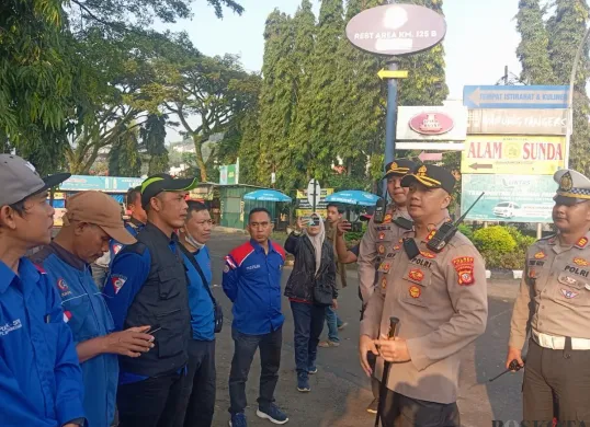 Kapolres Cimahi AKBP Niko Nurallah Adi Putra (Depan) memberikan pengarahan kepada buruh sebelum keberangkatan ke Jakarta, di Rest Area KM 125 Cipularang, Kamis 1 Mei 2025. (Sumber: Poskota/Gatot Poedji Utomo)