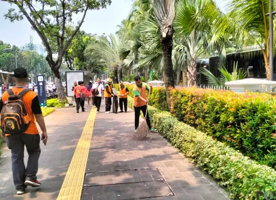 Petugas kebersihan Dinas Lingkungan Hidup (DLH) DKI Jakarta saat membersihkan sampah masa buruh di depan Balai Kota DKI Jakarta. (Sumber: Poskota/M. Tegar Jihad)
