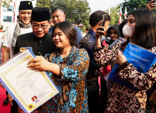 Warga menerima ijazah dari program pemutihan ijazah di Balai Kota Jakarta, Jum'at, 2 Mei 2025. Pada program tersebut, Gubernur Jakarta Pramono Anung menyerahkan ijazah yang tertunda kepada 371 siswa. (Sumber: Poskota/Bilal Nugraha Ginanjar)