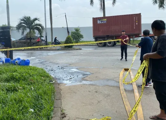 Personel Unit Reskrim Polsek Cikande memasang garis polisi di TKP truk pengangkut bahan kimia yang terbakar. (Sumber: Polsek Cikande)