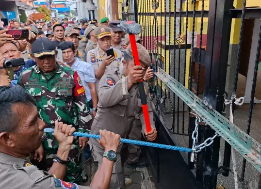 Petugas Satpol PP Kota Depok menggunakan linggis untuk membongkar paksa rantai yang mengunci gerbang SDN Utan Jaya, Cipayung, Kota Depok, Kamis, 8 Mei 2025. (Sumber: Poskota/Angga Pahlevi)