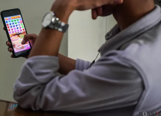 Seorang warga bermain judi online di kawasan perkantoran Palmerah, Jakarta Barat, Jum'at, 9 Mei 2025. (Sumber: Poskota/Bilal Nugraha Ginanjar)