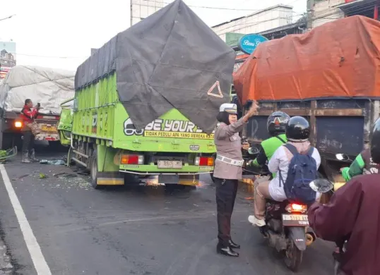 Polisi mengatur arus lalu lintas di sekitar TKP kecelakaan yang melibatkan dua unit truk kawasan Jalan Raya Jakarta-Bogor, Kecamatan Bogor Utara, Kota Bogor. (Sumber: Poskota/Sekar Putri Andini)