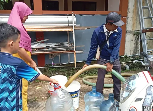 Warga Perumahan Panjibuwono, Kecamatan Babelan, Kabupaten Bekasi, mengantre untuk mendapatkan air bersih gratis dari PDAM Tirta Bhagasasi, Rabu, 14 Mei 2025. (Sumber: Poskota/Nurpini Aulia Rapika)