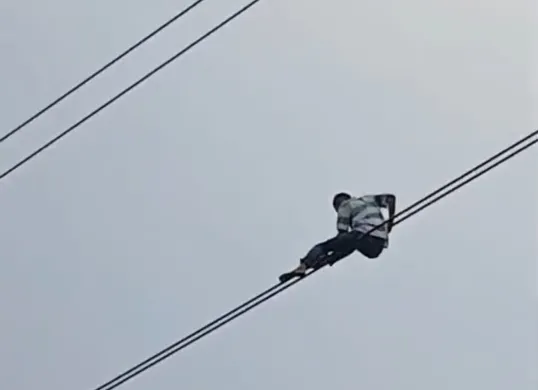 Seorang pria nekat bergelantungan di kabel udara di Jalan Gatot Subroto, Setiabudi, Jakarta Selatan. (Sumber: Istimewa)