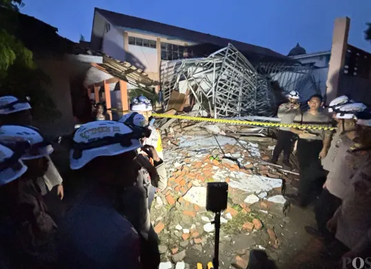 Sejumlah polisi berjaga di lokasi ambruknya atap ruang kelas SMKN 1 Gunung Putri, Kabupaten Bogor. (Sumber: POSKOTA | Foto: Giffar Rivana)