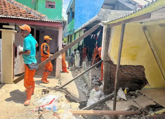 Petugas PPSU membantu membersihkan bangunan warga yang rusak akibat tanah amblas di GG Sumur Jambu, Kelurahan/Kecamatan Makasar, Jaktim. (Sumber: POSKOTA | Foto: M Tegar Jihad)