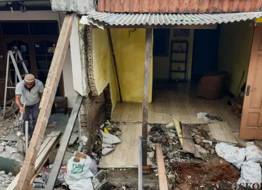 Warga membersihkan puing-puing rumahnya yang hancur akibat pergerakan tanah di Gang Sumur Jambu, Makasar, Jakarta Timur. (Sumber: Poskota/Bilal Nugraha Ginanjar)