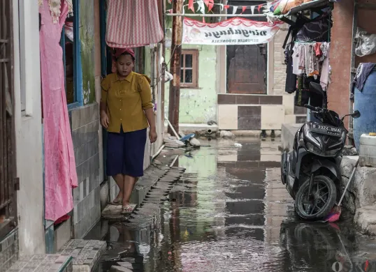 Warga melintasi genangan banjir rob di Muara Angke, Jakarta Utara, Rabu, 5 November 2025. (Sumber: Poskota/Bilal Nugraha Ginanjar)
