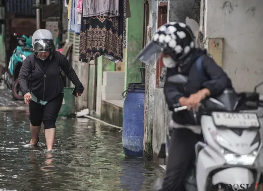 Ilustrasi - Warga melintasi genangan banjir. (Sumber: Poskota/Bilal Nugraha Ginanjar)