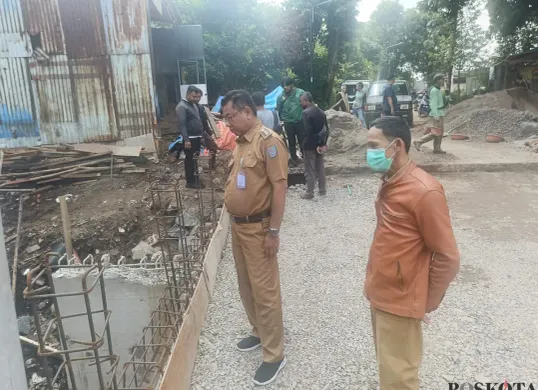 Lurah Krukut Ron Mahendra Jaya bersama petugas kelurahan saat meninjau lokasi pekerjaan jembatan Jalan Rawa Jati. (Sumber: Poskota/Angga Pahlevi)