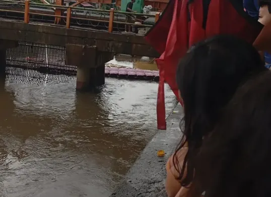 Warga menyaksikan evakuasi mayat pria yang diduga hanyut di aliran Kali Pesanggrahan wilayah Kembangan, Jakarta Barat, Sabtu, 8 November 2025. (Sumber: Istimewa)