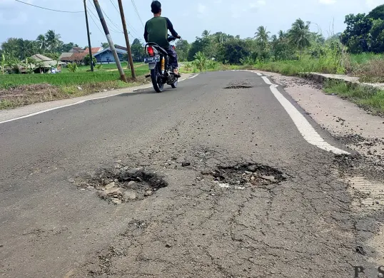 Pengendara roda dua melintas di jalan Babakan Sompok-Kadumadang di Cimanuk, Pandeglang, yang kondisinya rusak lagi. (Sumber: POSKOTA | Foto: Samsul Fatoni)