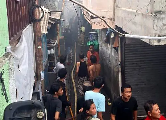 Petugas damkar berjibaku memadamkan api yang membakar sebuah rumah di Gang Pelita, Kelurahan Jatipulo, Palmerah, Jakarta Barat, Minggu, 16 November 2025. (Sumber: Dok Gulkarmat Jakarta Barat)