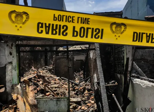 Warga berjalan di sekitar lokasi kebakaran akibat putusnya ground steel wire jaringan saluran udara tegangan tinggi di RW 004 Jatipulo, Jakarta Barat, Senin, 17 November 2025. (Sumber: Poskota/Bilal Nugraha Ginanjar)