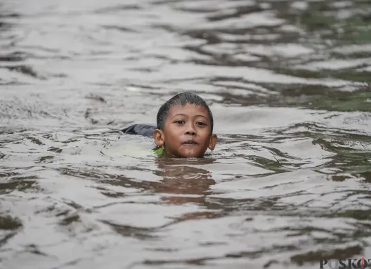 Seorang anak berenang pada genangan banjir di Jakarta. (Sumber: Poskota/Bilal Nugraha Ginanjar)