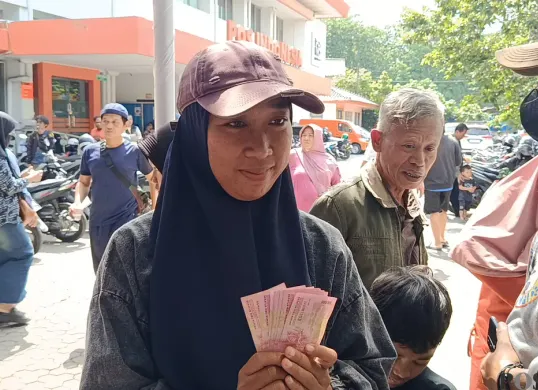 Salah seorang penerima bansos BLT Kesra di Kantor Pos Indonesia, Jalan Lapangan Serbaguna Nomor 7, RT 002/RW 009, Kelurahan Margahayu, Kecamatan Bekasi Timur, Kota Bekasi, Senin, 24 November 2025. (Sumber: Poskota/Nurpini Aulia Rapika)