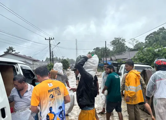 Relawan mendistribusikan paket MBG kepada warga yang terdampak banjir di Tapanuli Selatan meski akses jalan dipenuhi lumpur. (Sumber: Biro Hukum dan Humas BGN)