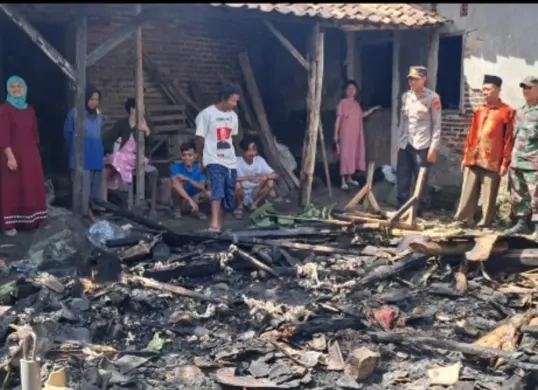 Kapolsek Cikeusal Iptu Hairus Saleh saat melihat kondisi rumah Arkiman yang rata dengan tanah setelah dilalap si jago merah. (Sumber: Polsek Cikeusal)