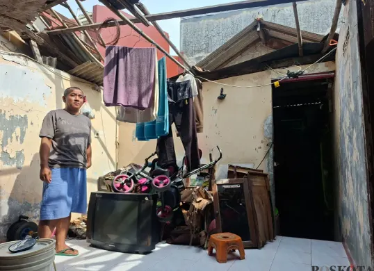 Dodi, 40 tahun, berdiri di area rumahnya yang mengalami kerusakan parah pada bagian atap di Depok. Kondisi rumah tanpa atap membuat para penghuninya terpaksa mengungsi saat turun hujan. (Sumber: Poskota/Angga Pahlevi)