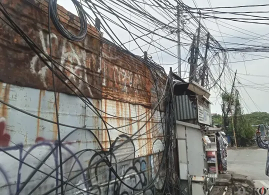 Penampakan kabel semeratut bahkan menjuntai ke bawah di Jalan Raya Kapuk, Penjaringan, Jakarta Utara, Jumat, 3 Oktober 2025. (Sumber: Poskota/Pandi Ramedhan)