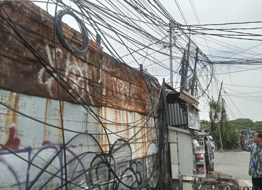 Penampakan kabel semeratut bahkan menjuntai ke bawah di Jalan Raya Kapuk, Penjaringan, Jakarta Utara, Jumat, 3 Oktober 2025. (Sumber: Poskota/Pandi Ramedhan)