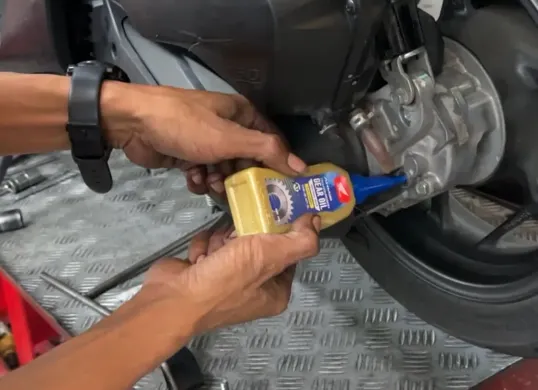 Mekanik sedang memeriksa dan mengganti oli gardan pada motor matik untuk menjaga performa dan keawetan komponen transmisi akhir. (Sumber: Istimewa)