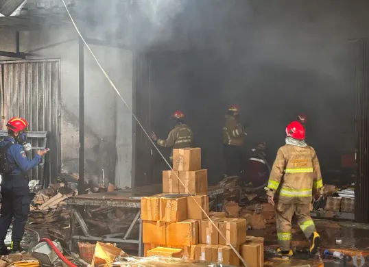 Petugas pemadam melakukan pendinginan di pabrik bingkai yang terbakar pada Selasa pagi 7 Oktober 2025, di Jalan Cikaret, Cibinong, Kabupaten Bogor. (Sumber: Poskota/M. Tegar Jihad)