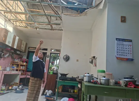 Asep pemilik rumah di Limo, Kota Depok, menunjukan atap rumah yang rusak akibat terkena angin puting beliung. (Sumber: Poskota/Angga Pahlevi)