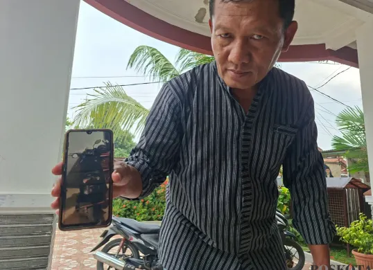Orang tua korban, H. Alvian, memperlihatkan foto motor anaknya yang hilang dicuri. (Sumber: Poskota/Angga Pahlevi)