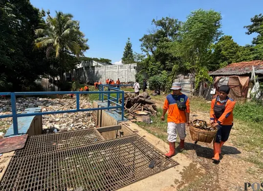 Petugas tim reaksi cepat DLH Kabupaten Bogor membersihkan sampah irigasi Setu Cikaret. (Sumber: Poskota/Giffar Rivana)