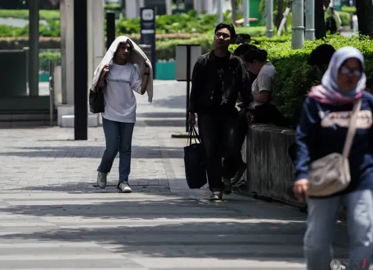 Warga berjalan di tengah cuaca terik di Jalan Jenderal Sudirman, Jakarta, beberapa waktu lalu. (Sumber: Poskota/Bilal Nugraha Ginanjar)