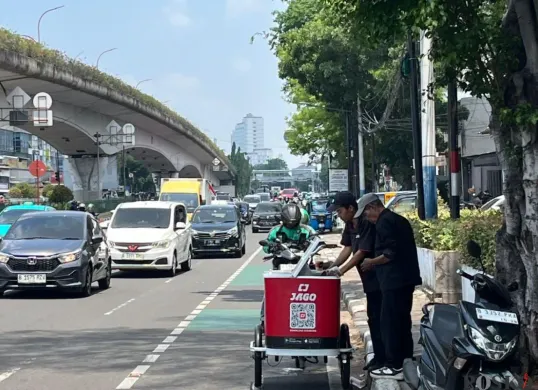 Pedagang kopi keliling melayani pembeli saat cuaca panas di kawasan Johar Baru, Jakarta Pusat, Kamis, 16 Oktober 2025. (Sumber: Poskota/M. Tegar Jihad)