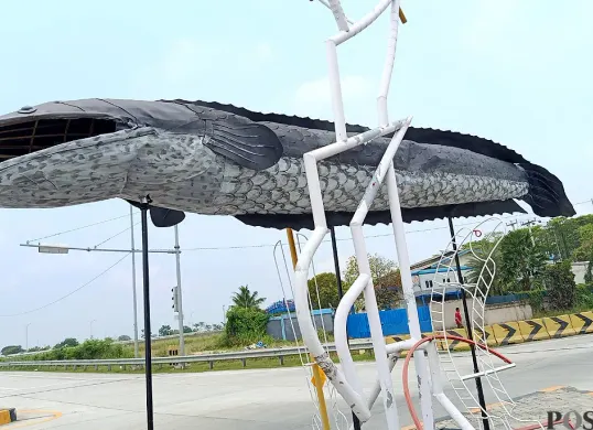 Penampakan patung ikan gabus yang berdiri di depan exit Tol Gabus, Desa Srijaya, Kecamatan Tambun Utara, Kabupaten Bekasi. (Sumber: POSKOTA | Foto: Nurpini Aulia Rapika)