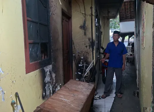 Pemilik kontrakan, H. Mahrub, 63 tahun, menunjukkan kondisi rumah kontrakan di Ciganjur, Jakarta Selatan, yang hangus terbakar setelah disiram bensin oleh mantan pacar penghuni, Jumat, 17 Oktober 2025, subuh. (Sumber: Poskota/Angga Pahlevi)
