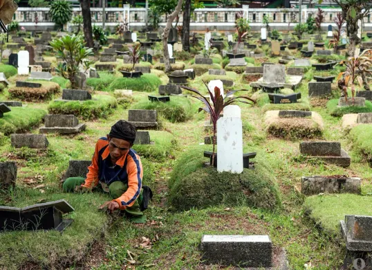 Petugas sedang membersihkan rumput di TPU Grogol Selatan, Kecamatan Kebayoran Lama, Jakarta Selatan. (Sumber: POSKOTA | Foto: Bilal Nugraha Ginanjar)