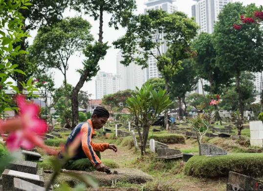 Petugas Suku Dinas Pertamanan dan Hutan Jakarta Selatan membersihkan salah satu makam di Tempat Pemakaman Umum (TPU) Grogol Selatan, Jakarta, Selasa, 21 Oktober 2025. (Sumber: Poskota/Bilal Nugraha Ginanjar)