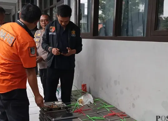 Anggota Polsek Lembang Polres Cimahi, menunjukan menu santap siang gratis. (Sumber: Poskota/Gatot Poedji Utomo)